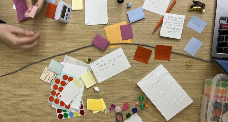 An early POV prototype made of sticky notes, index cards, a timer, and tokens spread across a table